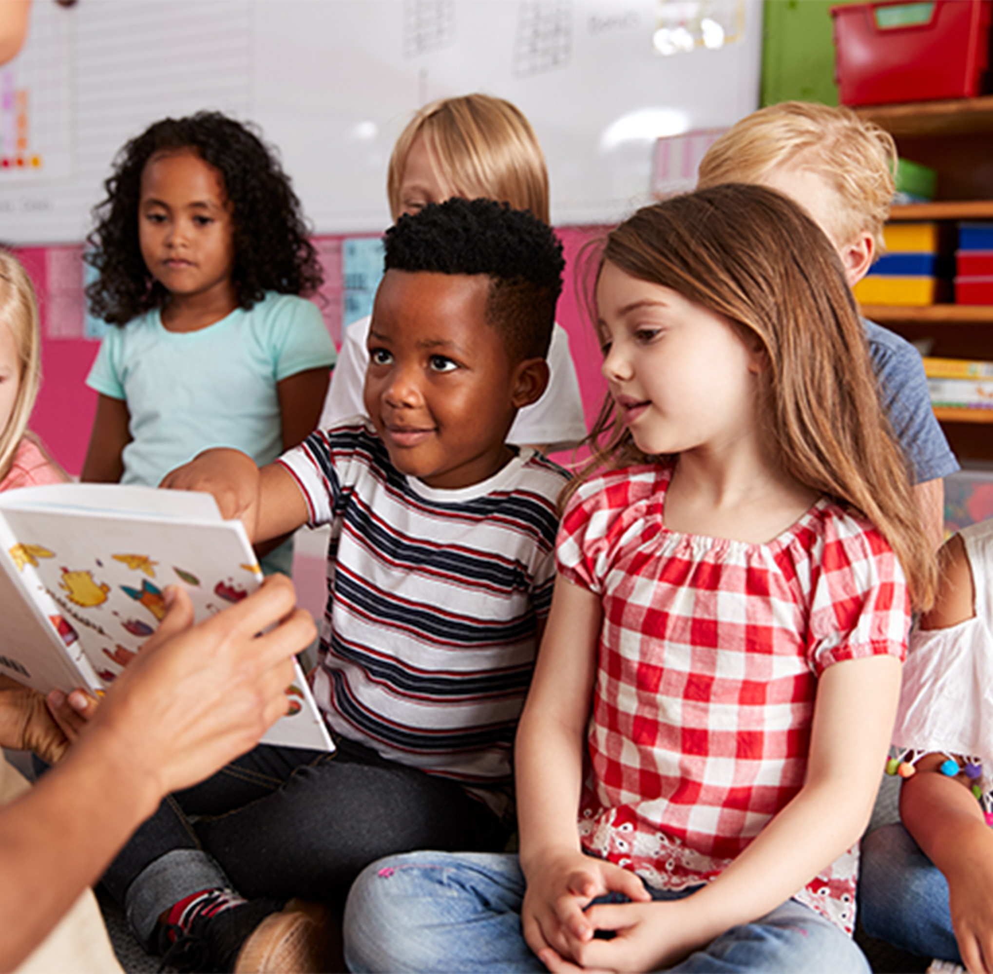 two young students looking at book from teacher