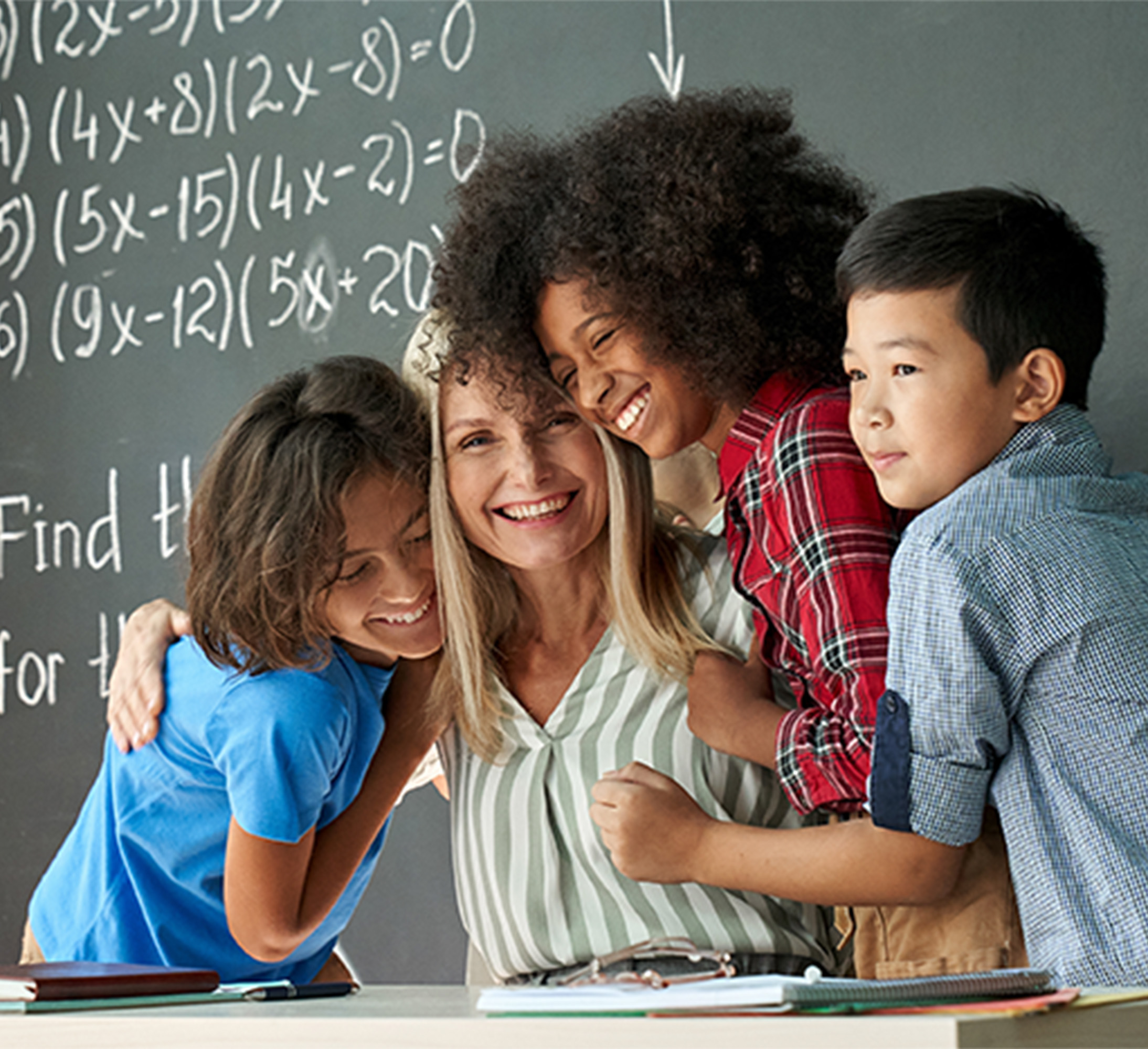 teacher with students in classroom happy and hugging